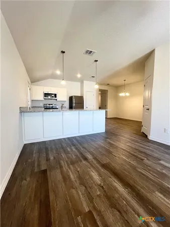 a view of a kitchen with kitchen island a sink wooden floor and stainless steel appliances