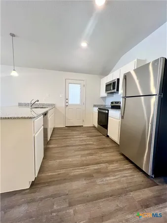 a kitchen with stainless steel appliances granite countertop a refrigerator and a stove
