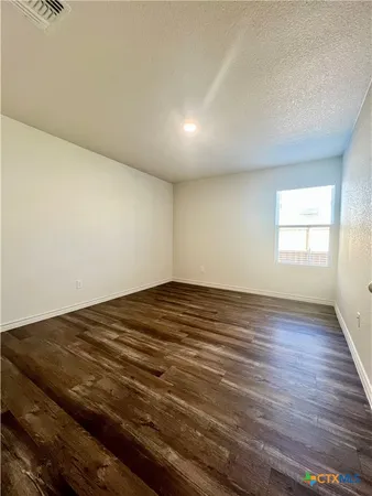 an empty room with wooden floor and window