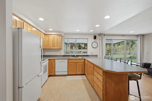 a kitchen with stainless steel appliances granite countertop a refrigerator a sink dishwasher a oven with white cabinets and wooden floor