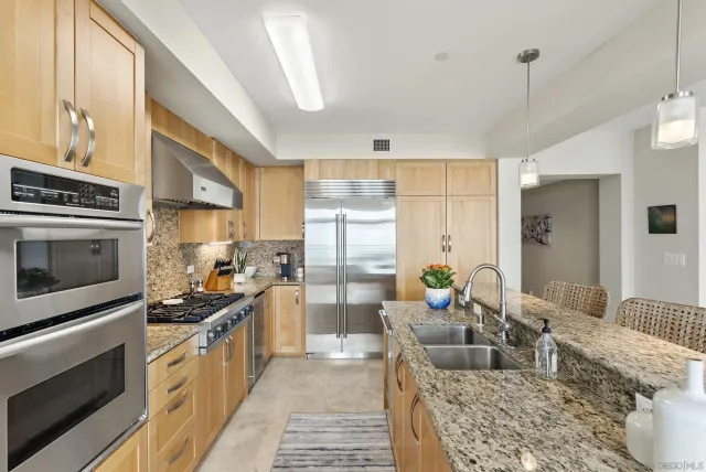 a kitchen with stainless steel appliances granite countertop a stove a sink and a refrigerator