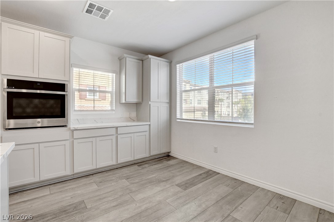 2555 Hampton Road, Unit 2207 Henderson, NV 89052 - Photo 16 of 74 A well-lit kitchen area features a built-in oven and ample white cabinetry, all set upon durable flooring.