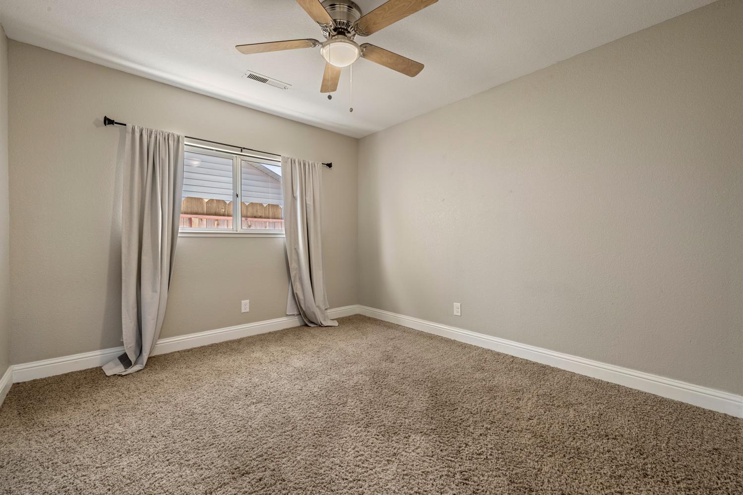 3317 Shamrock Avenue Merced, CA 95340 - Photo 22 of 44 an empty room with windows and fan