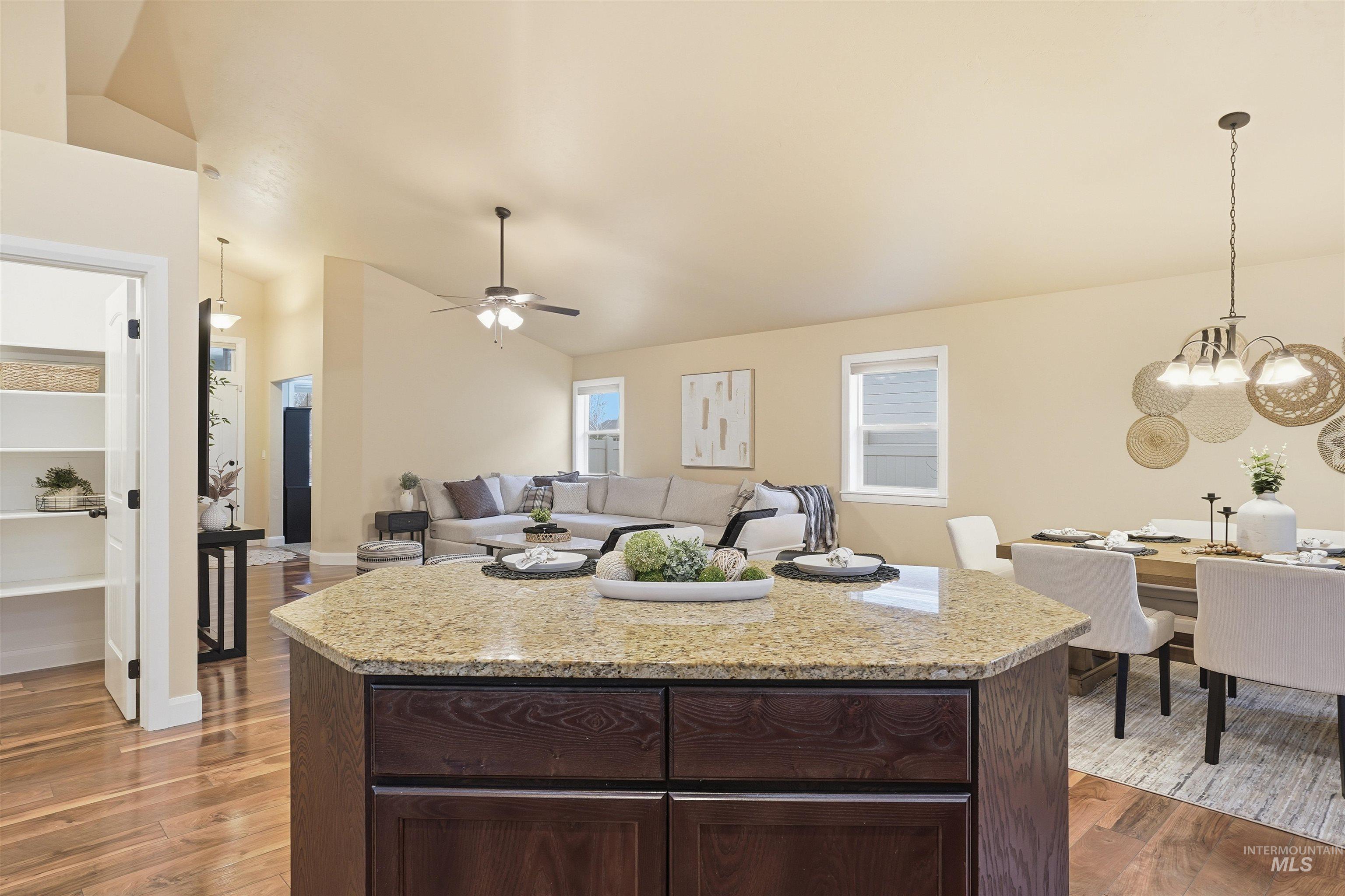 5697 Combermere Drive Eagle, ID 83616 - Photo 12 of 43 Kitchen featuring hanging light fixtures, dark brown cabinetry, lofted ceiling, and light stone counters