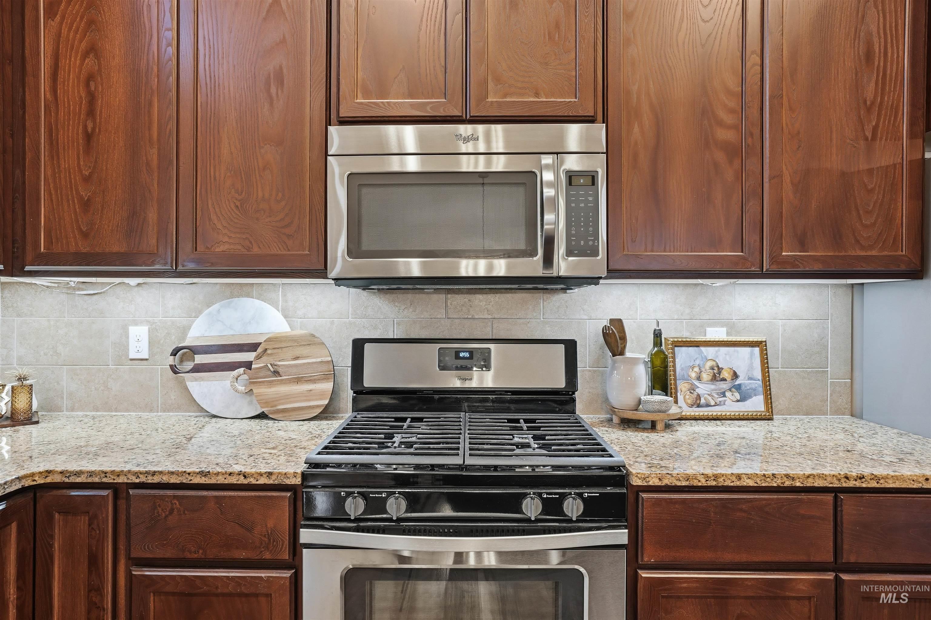 5697 Combermere Drive Eagle, ID 83616 - Photo 14 of 43 Kitchen featuring appliances with stainless steel finishes, light stone counters, and decorative backsplash
