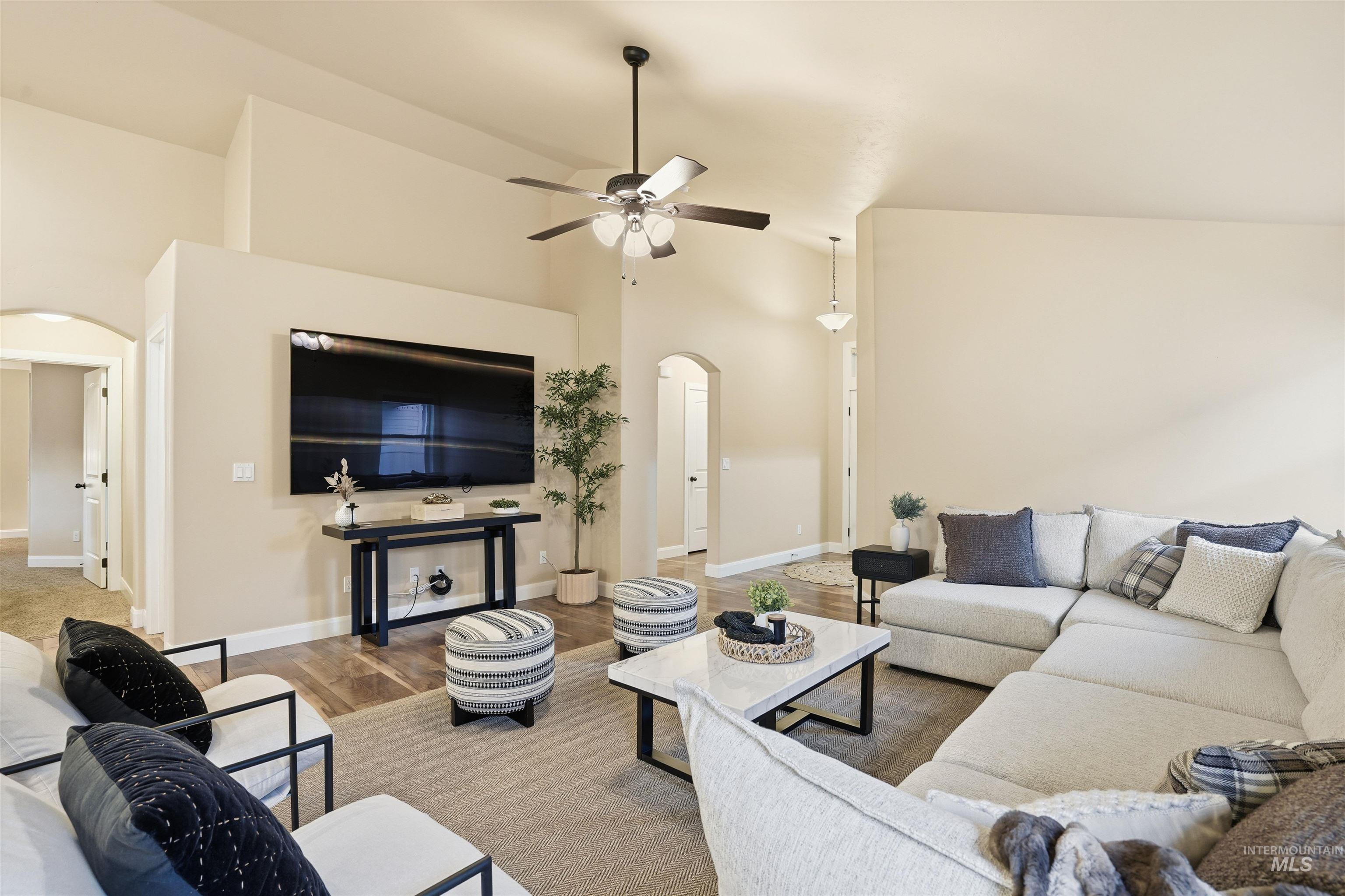 5697 Combermere Drive Eagle, ID 83616 - Photo 6 of 43 Living area featuring arched walkways, wood finished floors, high vaulted ceiling, and a ceiling fan