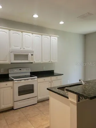 a kitchen with granite countertop white cabinets and white stove