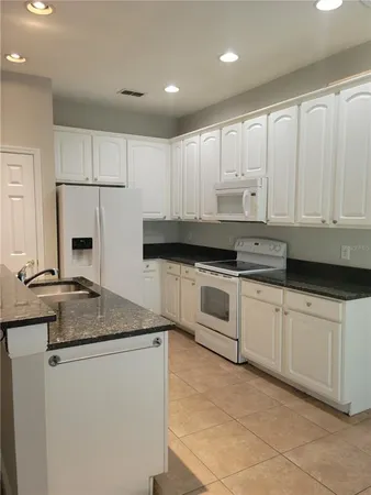 a kitchen with granite countertop white cabinets and white appliances