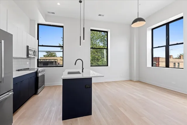 a kitchen with stainless steel appliances granite countertop a sink a stove and a wooden floor