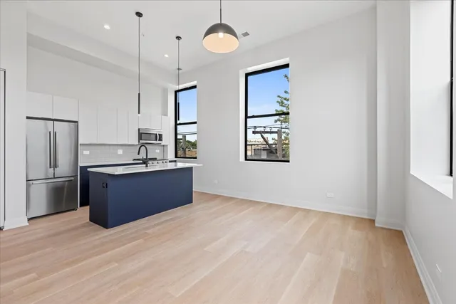 a kitchen with stainless steel appliances kitchen island a refrigerator sink and wooden floor