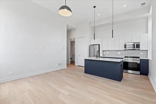 a large kitchen with kitchen island a sink stainless steel appliances and cabinets