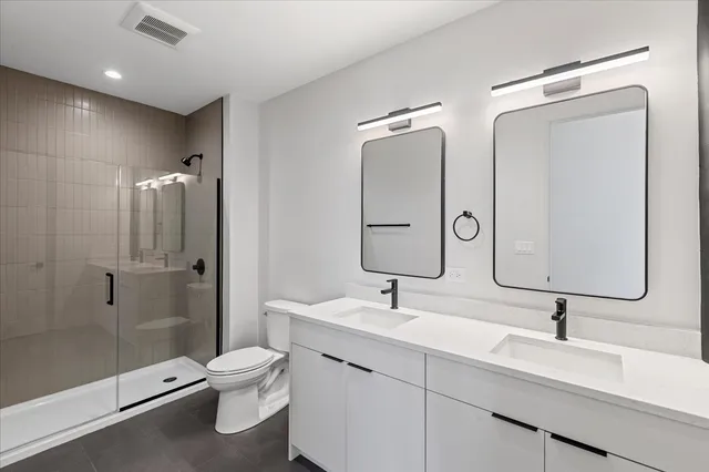 a bathroom with a double vanity sink toilet mirror and shower
