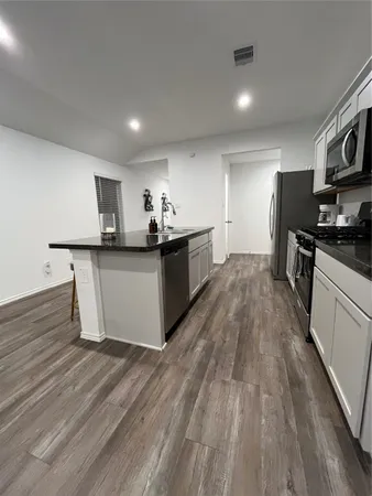 a kitchen with stainless steel appliances a stove top oven a sink dishwasher and a refrigerator