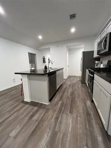 a kitchen with stainless steel appliances a stove top oven a sink dishwasher and a refrigerator