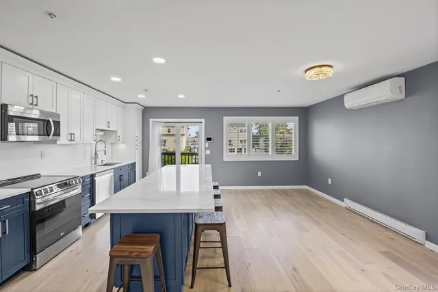 a living room with stainless steel appliances furniture a window and a kitchen view