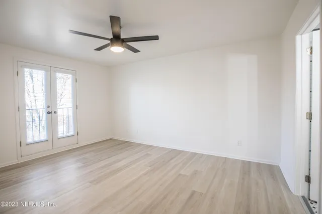 an empty room with wooden floor fan and windows