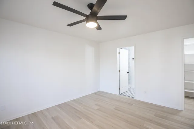 an empty room with wooden floor and a ceiling fan
