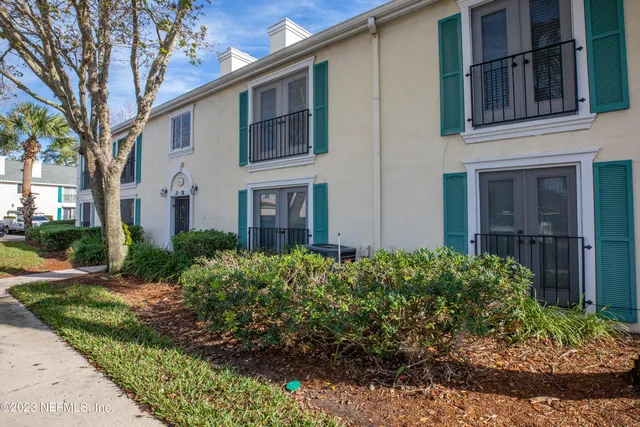 a view of a house with brick walls plants and large tree