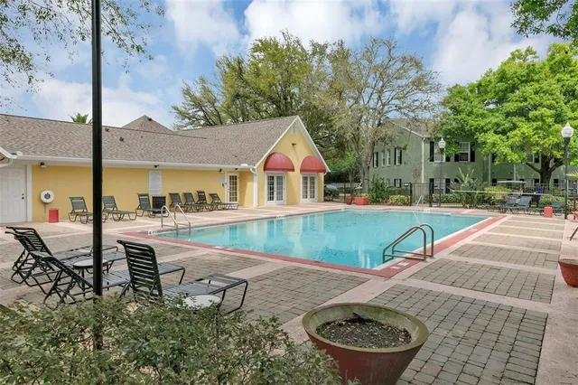 a view of swimming pool with lawn chairs and plants