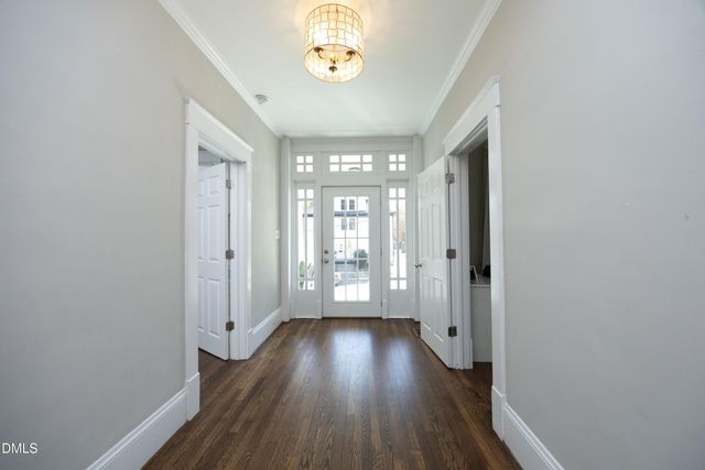 a view of a hallway with wooden floor and a chandelier