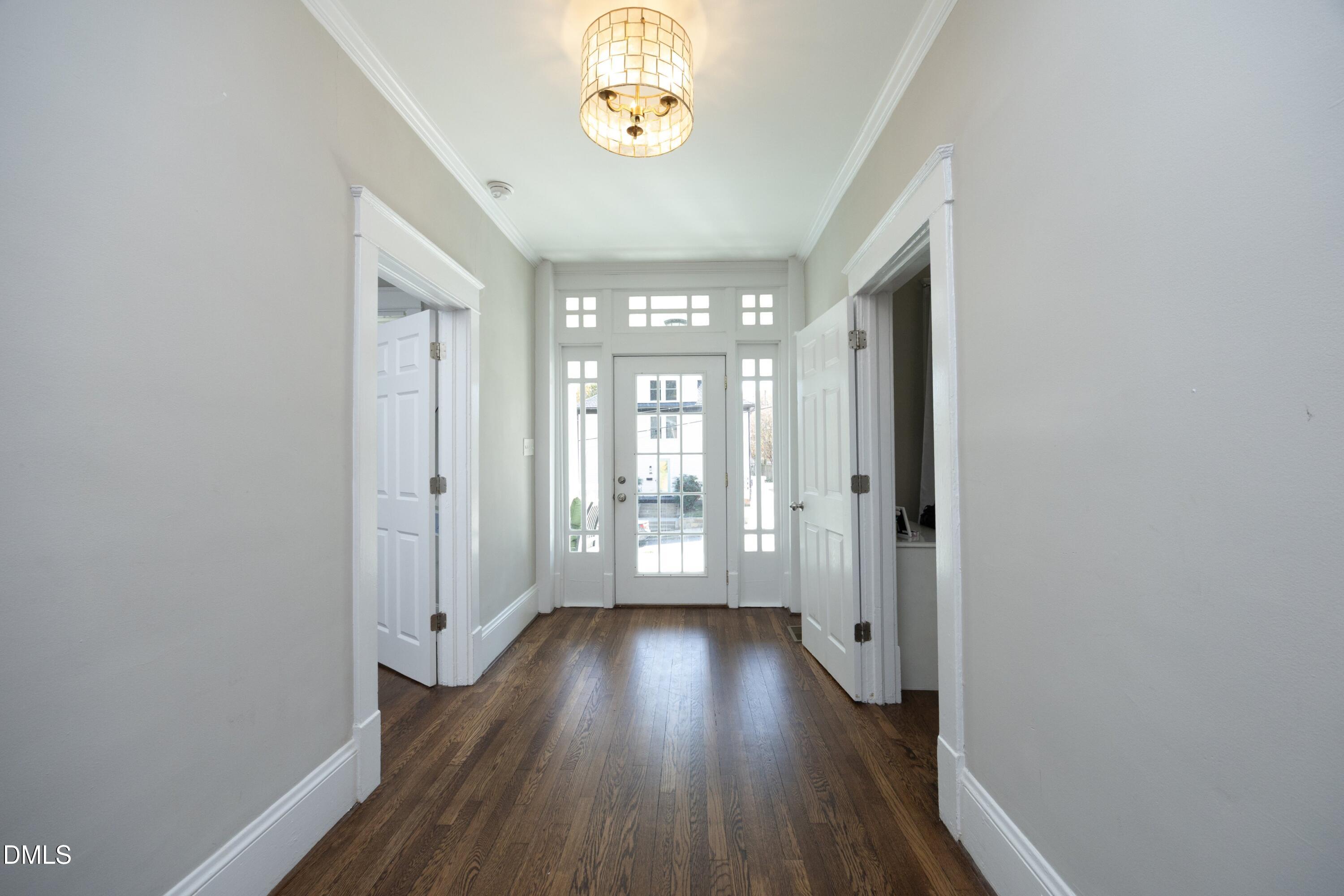 206 Ashe Avenue Raleigh, NC 27605 - Photo 5 of 37 a view of a hallway with wooden floor and a chandelier