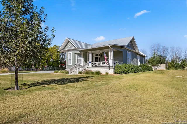 a view of a house with a big yard and large tree