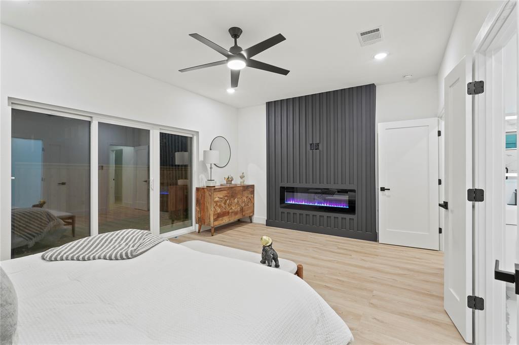 923 Walkway Street Dallas, TX 75212 - Photo 8 of 33 Bedroom featuring a glass covered fireplace, wood finished floors, a ceiling fan, recessed lighting, and access to outside