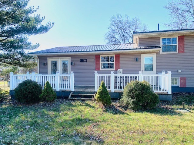 Rear view of property featuring a deck and a lawn