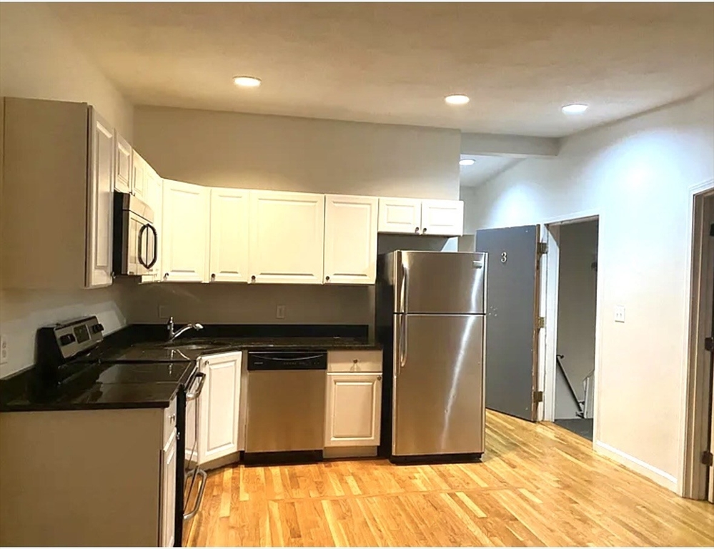206 H Street, Unit 3 Boston, MA 02127 - Photo 2 of 8 a kitchen with stainless steel appliances granite countertop a refrigerator a stove and a sink with wooden floor