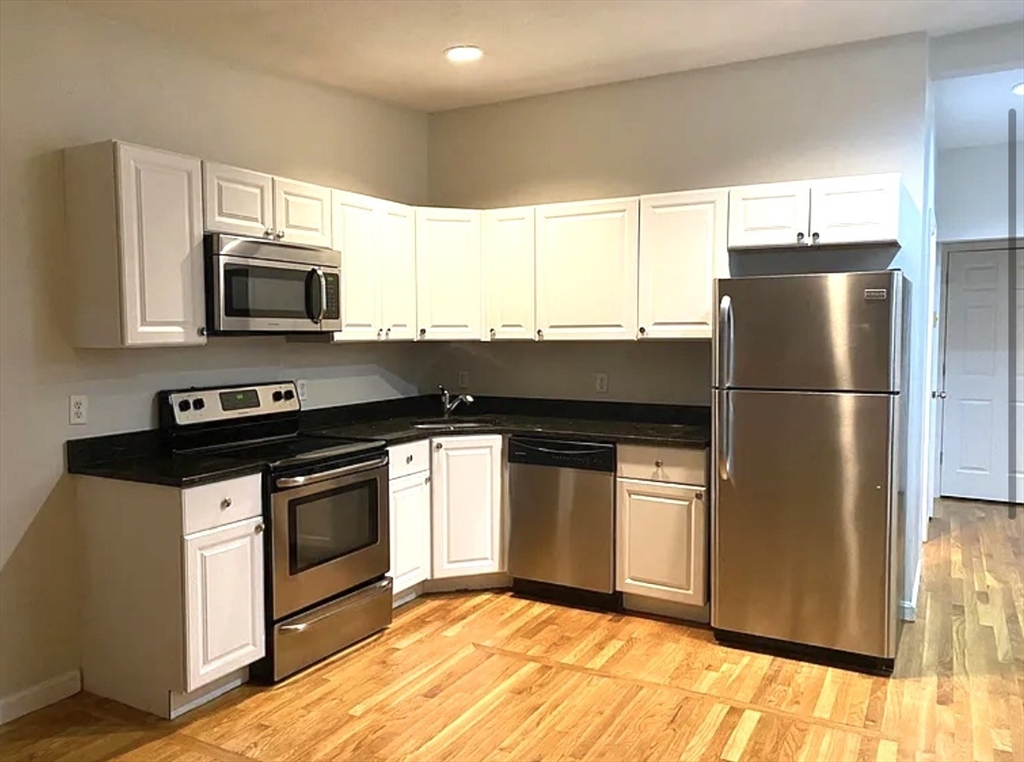 206 H Street, Unit 3 Boston, MA 02127 - Photo 3 of 8 a kitchen with granite countertop a refrigerator and a stove top oven