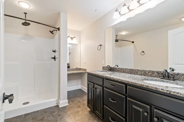 a bathroom with a granite countertop sink a mirror a shower and a bathtub