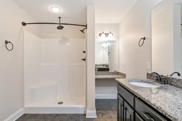 a bathroom with a granite countertop shower sink and mirror