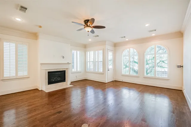 a view of a livingroom with wooden floor a fireplace and windows