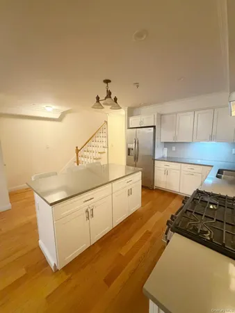 a kitchen with granite countertop a refrigerator a stove and white cabinets