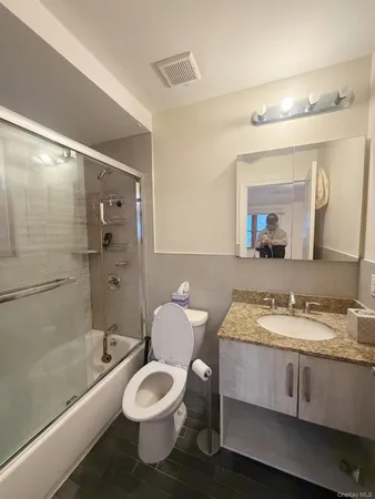a bathroom with a granite countertop toilet sink and mirror