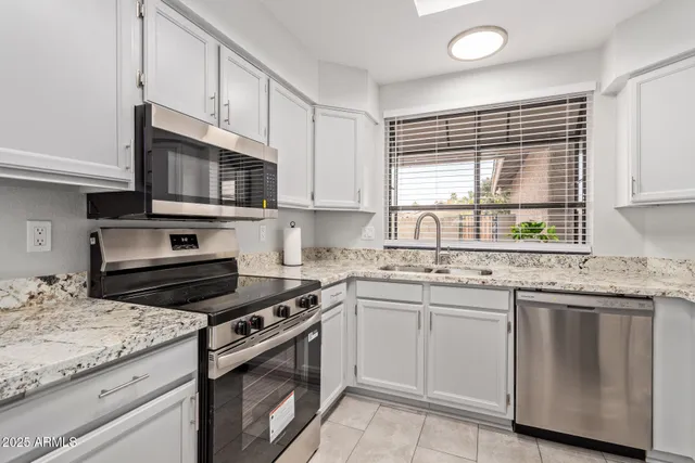 a kitchen with granite countertop a sink stove and cabinets