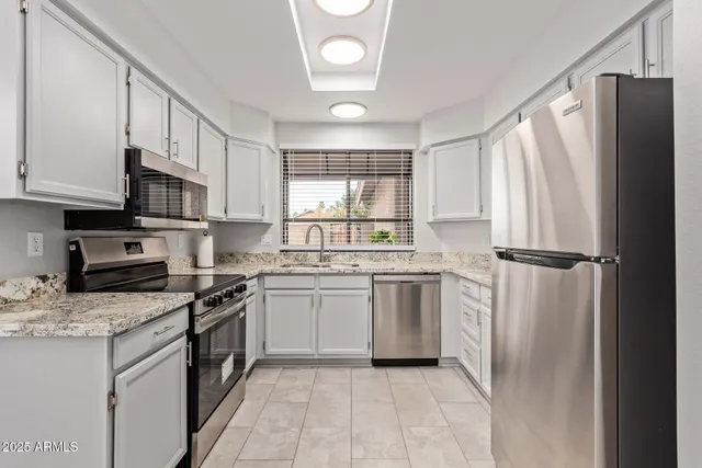 a kitchen with granite countertop a refrigerator stove top oven and sink