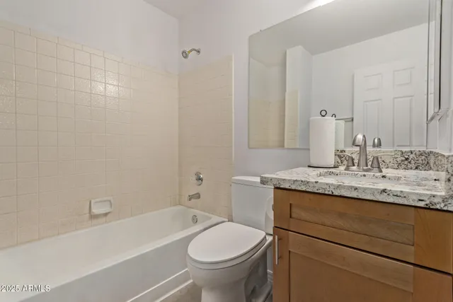 a bathroom with a granite countertop toilet a sink and a bathtub