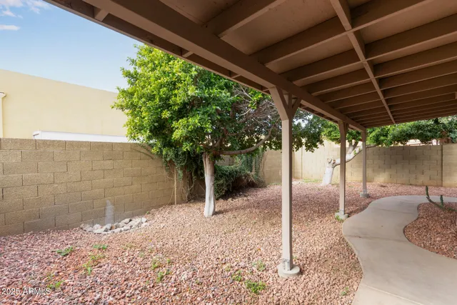 a backyard of a house with table and chairs under an umbrella
