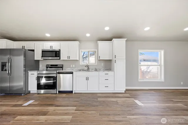 a kitchen with granite countertop white cabinets and stainless steel appliances