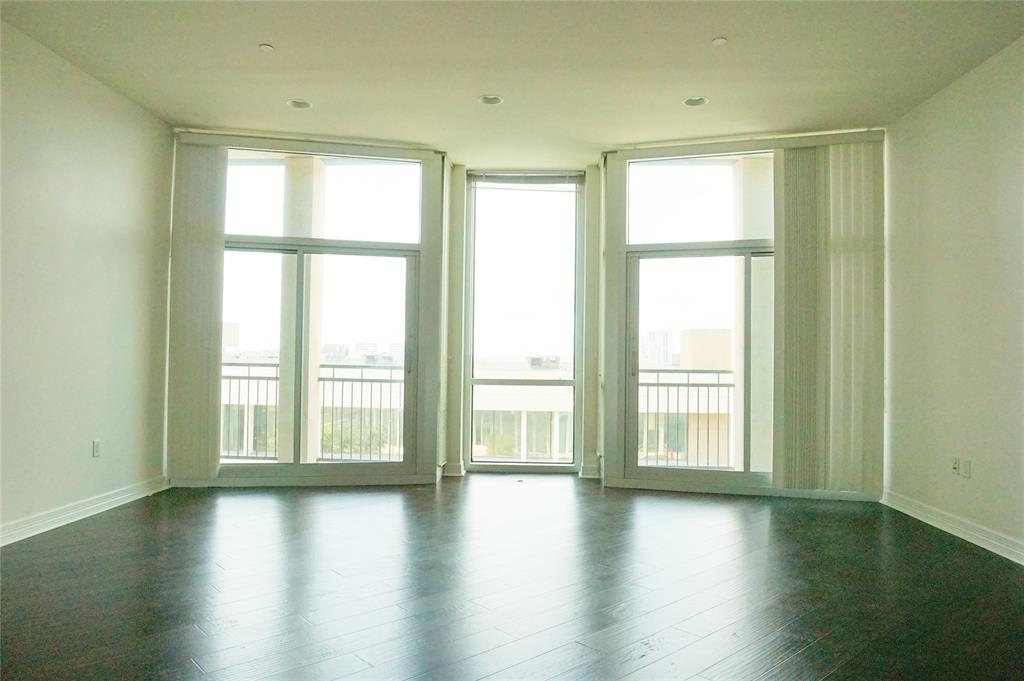 an empty room with wooden floor and windows with curtains