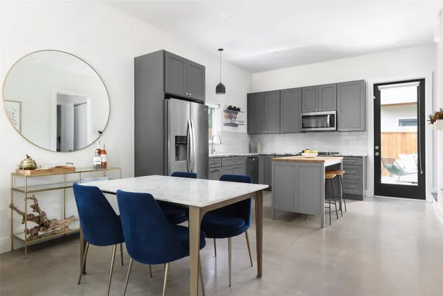 a open kitchen with stainless steel appliances kitchen island a table chairs and a refrigerator