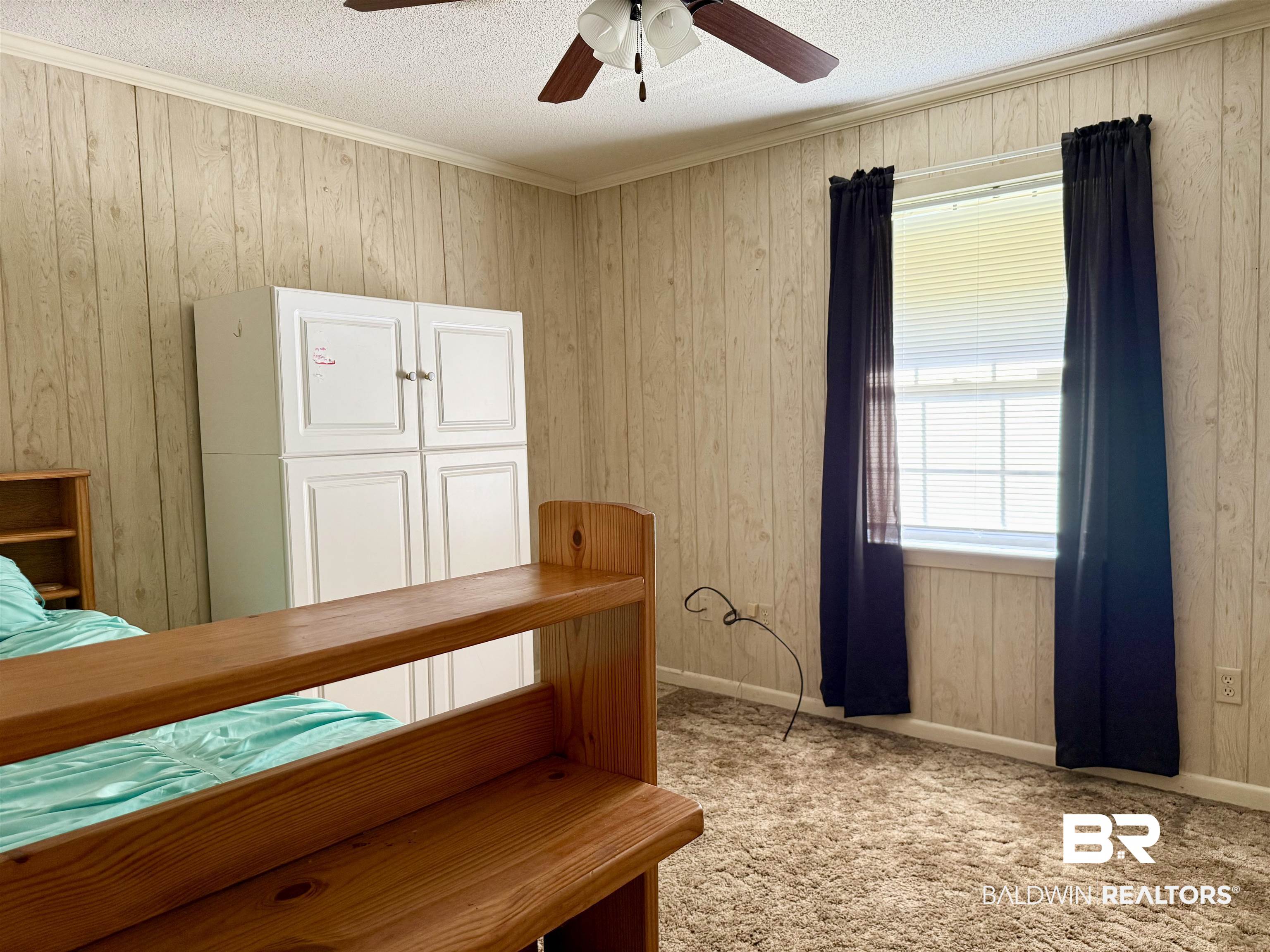 98 Evans Avenue Brewton, AL 36426 - Photo 10 of 18 Bedroom featuring wooden walls, ceiling fan, a textured ceiling, ornamental molding, and light colored carpet