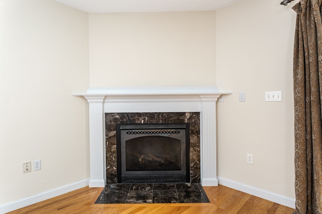 49 Beaver Street, Unit 49 Franklin, MA 02038 - Photo 13 of 46 a living room with a fireplace and a wooden floor
