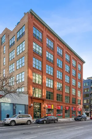 a front view of a building with lot of cars and trees