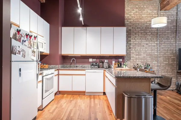 a kitchen with a stove a sink and white cabinets with wooden floor