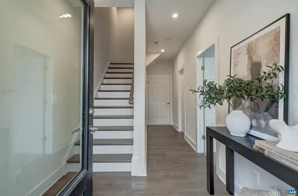 a hallway with wooden floor stairs and a potted plant