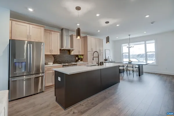 a kitchen with granite countertop a refrigerator a stove a sink and a dining table with wooden floor