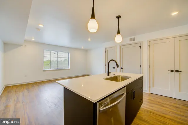 a kitchen that has a sink and a stove with wooden floor