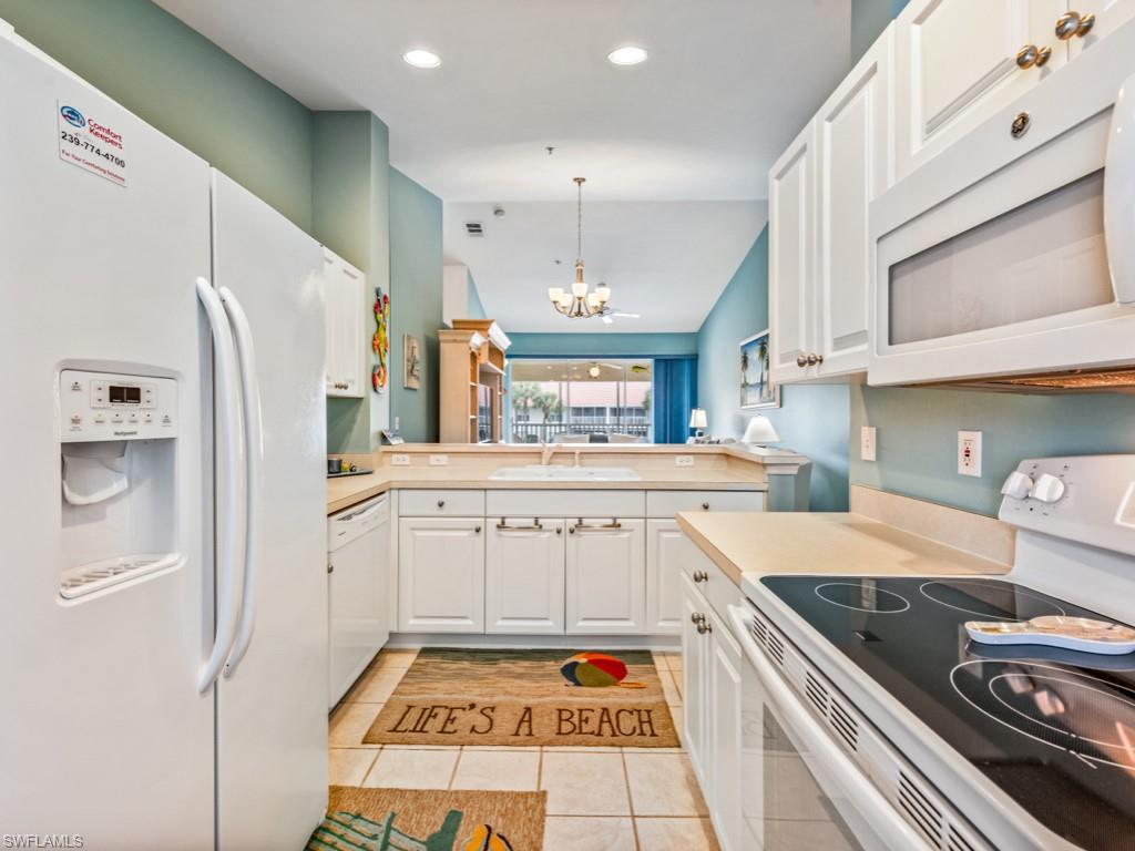 4970 Deerfield Way, Unit F202 Naples, FL 34110 - Photo 4 of 19 a kitchen with white cabinets and appliances